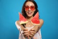 Beautiful young woman against blue background, focus on hands with watermelon