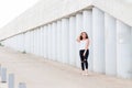 Beautiful young woman against the gray pillars and walls looking at the camera