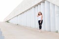 Beautiful young woman against the gray pillars and walls looking at the camera