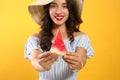 Beautiful young woman against yellow background, focus on hands with watermelon