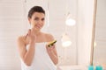 Beautiful young woman applying avocado facial mask in bathroom Royalty Free Stock Photo