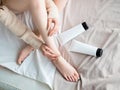 Beautiful young woman applying body lotion on bed sheet. Top view. Blank label for branding mock-up. Woman Skin Care