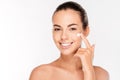 Beautiful young woman applying cosmetic cream treatment on her face Royalty Free Stock Photo