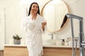 Beautiful woman applying cream onto face near mirror in bathroom Royalty Free Stock Photo