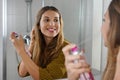 Beautiful young woman applying dry shampoo on her hair before going out. Fast and easy way to covering grey hair with instant Royalty Free Stock Photo