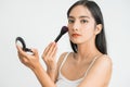 Beautiful young woman applying foundation powder or blush with makeup brush. Mixed race Asian Caucasian model. Royalty Free Stock Photo