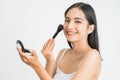 Beautiful young woman applying foundation powder or blush with makeup brush. Mixed race Asian Caucasian model. Royalty Free Stock Photo