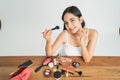 Beautiful young woman applying foundation powder or blush with makeup brush. Mixed race Asian Caucasian model. Royalty Free Stock Photo