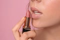 Beautiful young woman applying lipstick on color background, closeup Royalty Free Stock Photo