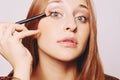 Beautiful young woman applying make up. Royalty Free Stock Photo