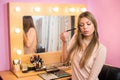 Beautiful young woman applying makeup near the mirror Royalty Free Stock Photo