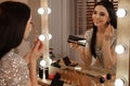 Beautiful woman applying makeup near mirror in dressing room Royalty Free Stock Photo