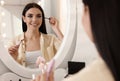 Beautiful young woman applying makeup near mirror Royalty Free Stock Photo