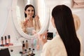 Beautiful young woman applying makeup near mirror indoors Royalty Free Stock Photo