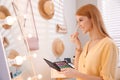 Beautiful young woman applying makeup near mirror in room Royalty Free Stock Photo