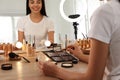 Beautiful young woman applying makeup at table with mirror and ring lamp Royalty Free Stock Photo