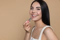 Beautiful young woman applying nude lipstick on beige background, space for text Royalty Free Stock Photo