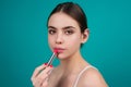 Beautiful young woman applying red lipstick on lips, studio color background. Sexy girl applied lipstick. Young nodel Royalty Free Stock Photo