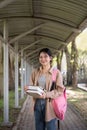 Beautiful young woman asian with backpack and book. College student carrying lots of books in college campus Royalty Free Stock Photo