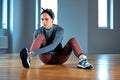 Beautiful young woman athlete tying shoelaces on sneakers while relaxing from strength training in the gym. oncept of Royalty Free Stock Photo