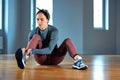 Beautiful young woman athlete tying shoelaces on sneakers while relaxing from strength training in the gym. oncept of