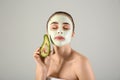Beautiful young woman with avocado facial mask on light background Royalty Free Stock Photo