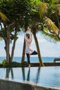 Beautiful young girl from the back makes yoga practice, meditation, standing pose in resort near the ocean beach Royalty Free Stock Photo