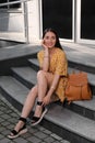 Beautiful young woman with backpack sitting on stairs outdoors Royalty Free Stock Photo