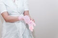 Beautiful young woman beautician in a white medical gown, on an isolated gray background. A woman doctor in a white coat puts