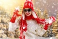 Beautiful young woman in a beautiful knitted hat, mitten and scarf walks in the winter forest. Fashionable knitted clothes. Royalty Free Stock Photo