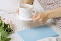 Beautiful young woman in bed drinking tea reading book