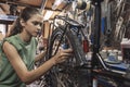 A beautiful young woman bicycle mechanic is repairing a bike in the workshop Royalty Free Stock Photo