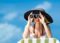 Beautiful young woman in bikini looking through binoculars at the tropical beach Royalty Free Stock Photo