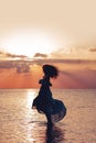 Elegant woman dancing on water. Sunset and silhouette Royalty Free Stock Photo