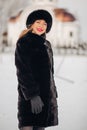 A beautiful young woman in a black fur hat and fur coat, portrait. A cute Russian girl smiles and looks into the frame Royalty Free Stock Photo