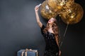 Beautiful young woman in black luxury dress, red lips, long curly brunette hair taking selfie portrait with big balloons Royalty Free Stock Photo