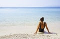 Beautiful young woman in a black swimsuit sits on the sand of a beach in Makarska, Croatia. Royalty Free Stock Photo