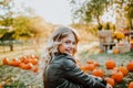 Beautiful young woman with blond hair sitting on a pumpkin`s field and smile Royalty Free Stock Photo