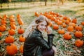 Beautiful young woman with blond hair sitting on a pumpkin`s field and smile Royalty Free Stock Photo