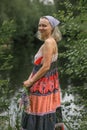 A beautiful young woman with blond hair in a sundress on the shore of a lake with a bouquet of wildflowers. National Russian Royalty Free Stock Photo