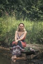 A beautiful young woman with blond hair in a sundress on the shore of a lake with a bouquet of wildflowers. National Russian Royalty Free Stock Photo