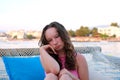 beautiful young woman, blonde with curly hair and blue eyes is sitting on a bench looking out to sea. The woman has the Royalty Free Stock Photo