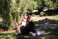 Beautiful young woman with blonde hair and blue eyes sits on park bench and poses for photo like a model. She is happy doing Royalty Free Stock Photo