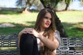 Beautiful young woman with blonde hair and blue eyes sits on park bench and poses for photo like a model. She is happy doing Royalty Free Stock Photo