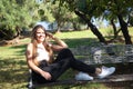 Beautiful young woman with blonde hair and blue eyes sits on park bench and poses for photo like a model. She is happy doing Royalty Free Stock Photo