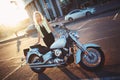 Beautiful young woman blonde standing near a motorcycle on the b Royalty Free Stock Photo