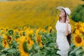 Beautiful young woman in blooming sunflowers field in summer. Stylish girl with long hair in white dress and hat. summer holiday Royalty Free Stock Photo