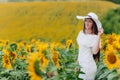 Beautiful young woman in blooming sunflowers field in summer. Stylish girl with long hair in white dress and hat. summer holiday Royalty Free Stock Photo