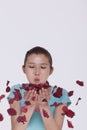 Beautiful young woman blowing a handful of rose petals, petals flying around in mid air Royalty Free Stock Photo