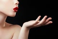 Beautiful young woman blowing a kiss from her hand. Model with perfect dark redl lips and manicured red nails Royalty Free Stock Photo